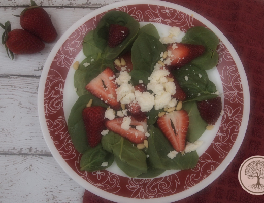 A plate with spinach and strawberry salad