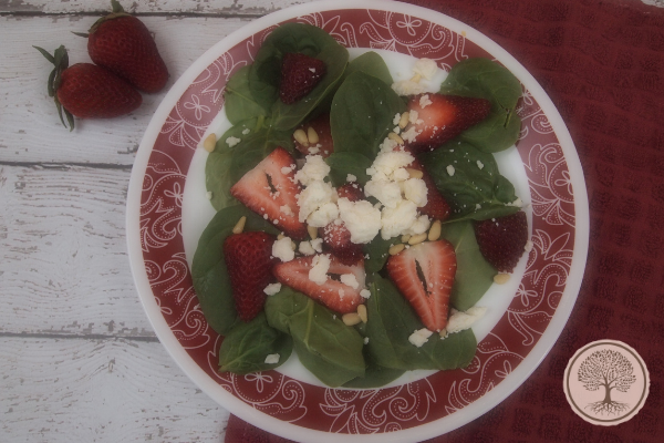 A plate with spinach and strawberry salad