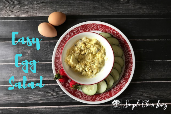 A picture of a bowl of egg salad on a plate with cucumbers and strawberries and the blog post title "Easy Egg Salad"