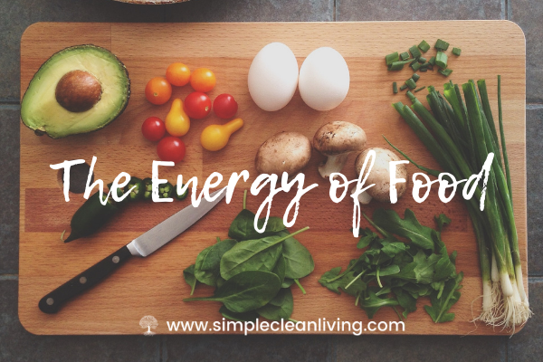 The Energy of Food- A cutting board with a knife, greens, herbs and vegetables