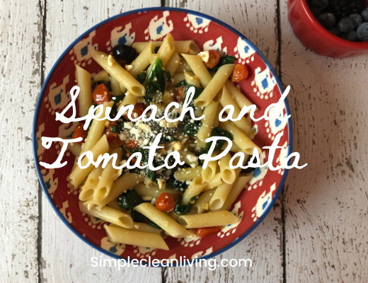 bowl of spinach and tomato pasta with the blog post title