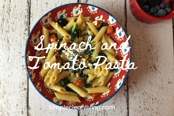 bowl of spinach and tomato pasta with the blog post title