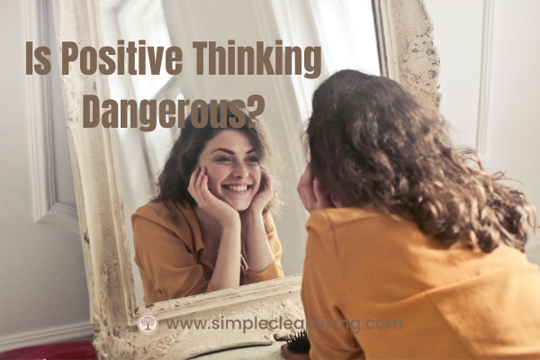 Is Positive Thinking Dangerous- Picture of woman staring at herself in mirror and smiling with the post title