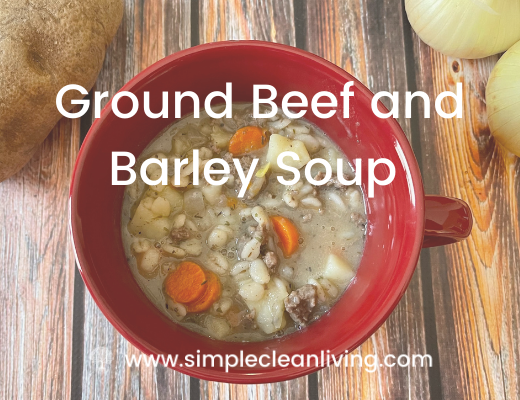 Ground Beef and Barley Soup in a red soup mug sitting on a wooden table