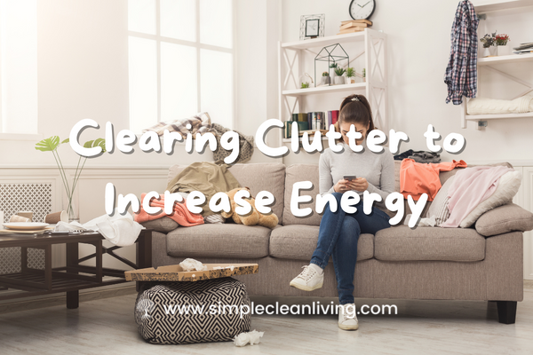 Clearing Clutter to Increase Energy blog post- Picture of a woman sitting on her couch in a very cluttered living room