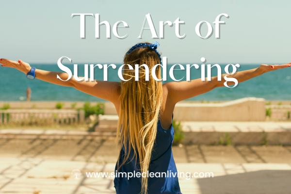 The Art of Surrendering- Picture of woman standing by the beach with both of her arms stretched up to the sky