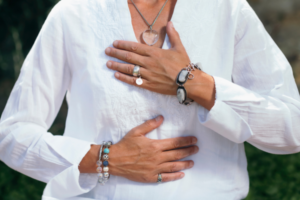Picture of woman wearing a white shirt standing with her hands on her chest in a relaxed pose